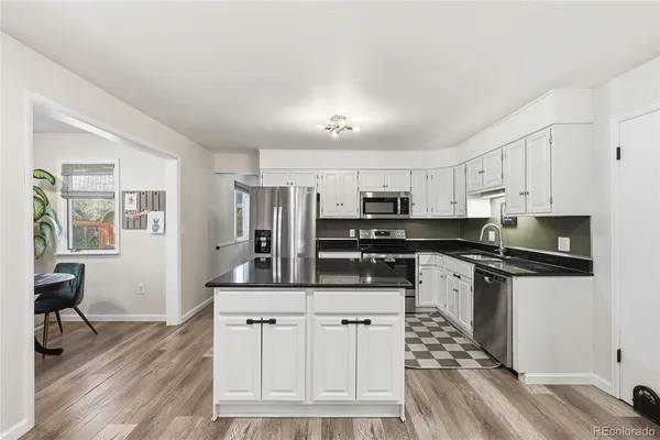 a kitchen with stainless steel appliances granite countertop a stove a sink dishwasher and a refrigerator with wooden floor