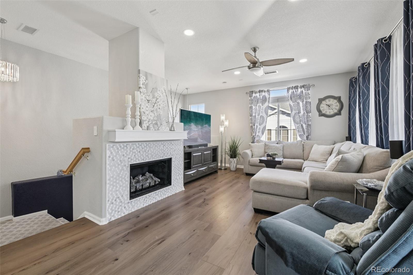 a living room with furniture a fireplace and a ceiling fan