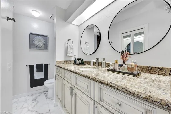 a bathroom with a granite countertop double vanity sink and a mirror
