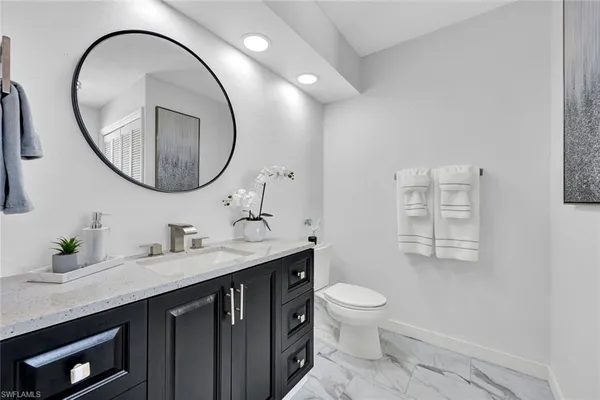 a bathroom with a granite countertop toilet a sink and a mirror