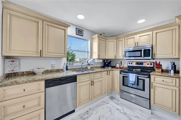 a kitchen with granite countertop white cabinets sink and stainless steel appliances