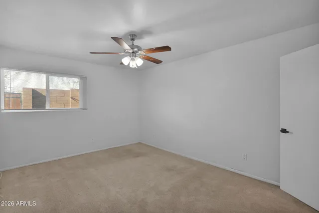 an empty room with a window and a fan