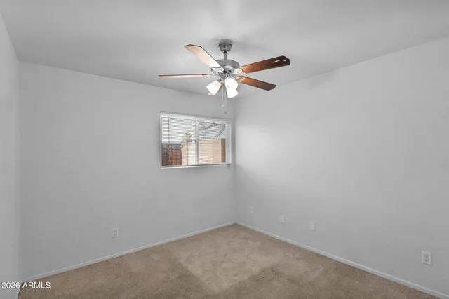 an empty room with a window and a fan