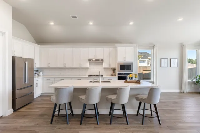 a kitchen with a dining table chairs refrigerator and cabinets