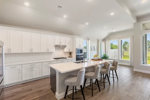 a kitchen with stainless steel appliances a table and chairs in it