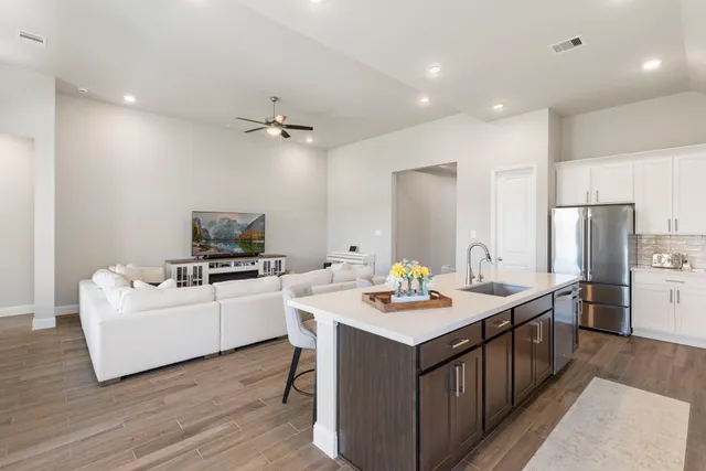 a kitchen with a sink a stove a refrigerator cabinets and wooden floor