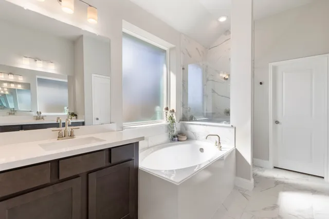 a bathroom with a sink double vanity granite tub shower and a mirror