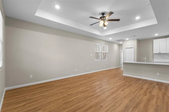 a view of an empty room with wooden floor and a ceiling fan