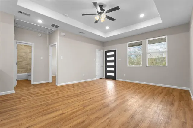 an empty room with wooden floor closet and windows