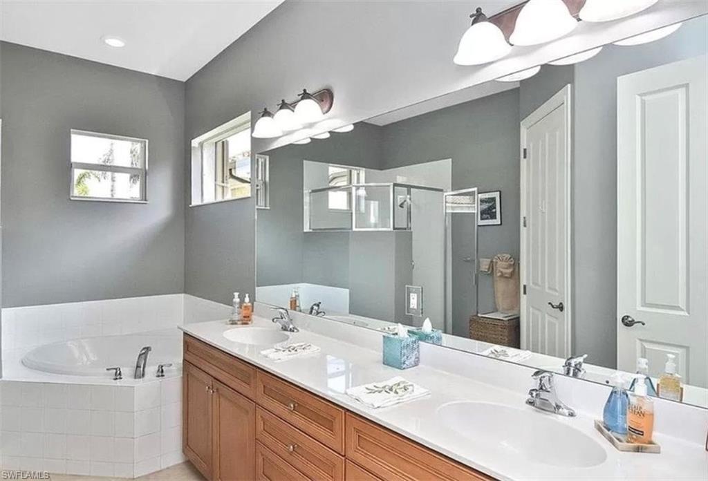 6044 Dogleg Drive Naples, FL 34113 - Photo 17 of 21 a bathroom with a sink a large mirror and a bathtub