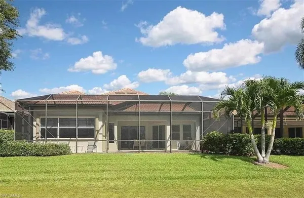 a view of a brick house with a big yard and large trees