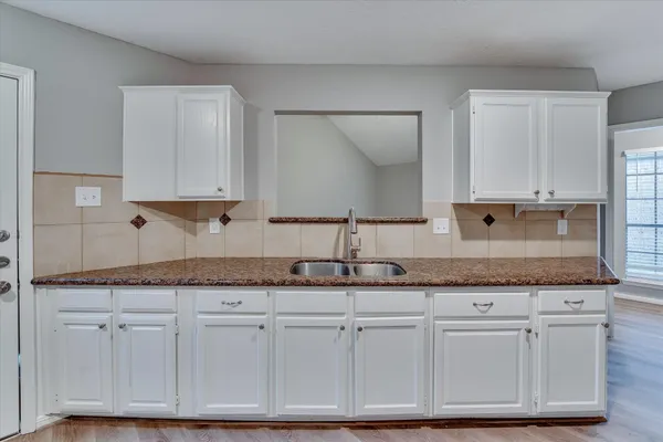 a kitchen with granite countertop stainless steel appliances white cabinets granite counter tops and a wooden floors