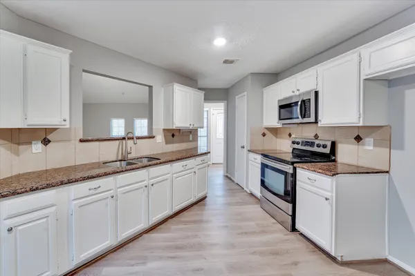 a large kitchen with stainless steel appliances granite countertop a stove a sink dishwasher and a microwave oven with wooden floor