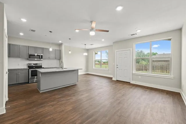 a large kitchen with stainless steel appliances granite countertop a large counter top a sink and a wooden floors