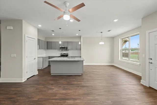 a view of kitchen with kitchen island stainless steel appliances wooden floor cabinets and a window