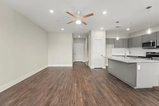 a open kitchen with kitchen island a sink dishwasher refrigerator stove and white cabinets with wooden floor