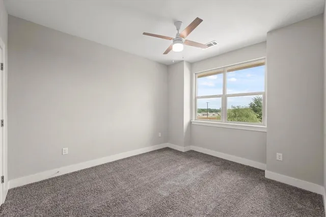 an empty room with windows and fan