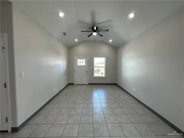 an empty room with chandelier fan and windows