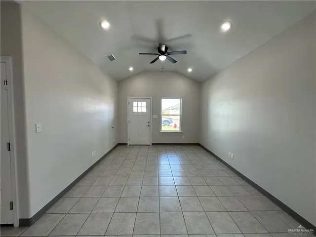 an empty room with chandelier fan and windows