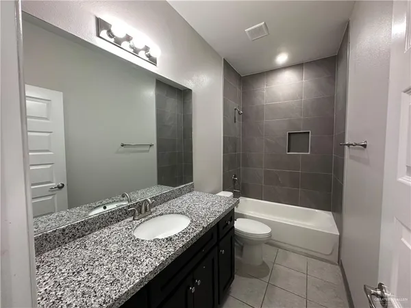 a bathroom with a granite countertop sink a toilet and shower