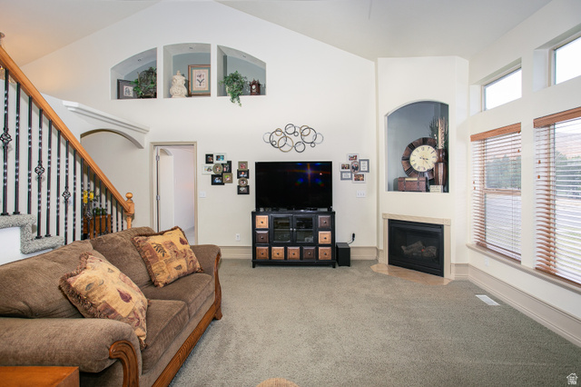 426 Deer Hollow Road Tooele, UT 84074 - Photo 9 of 37 Carpeted living area with a fireplace with flush hearth, stairway, and a towering ceiling