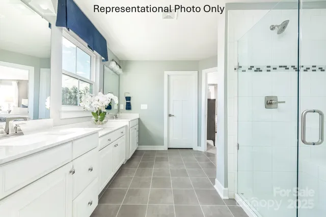 a spacious bathroom with a double vanity sink a mirror and a shower