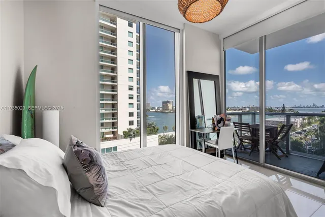 a bedroom with a bed and a large mirror next to a window