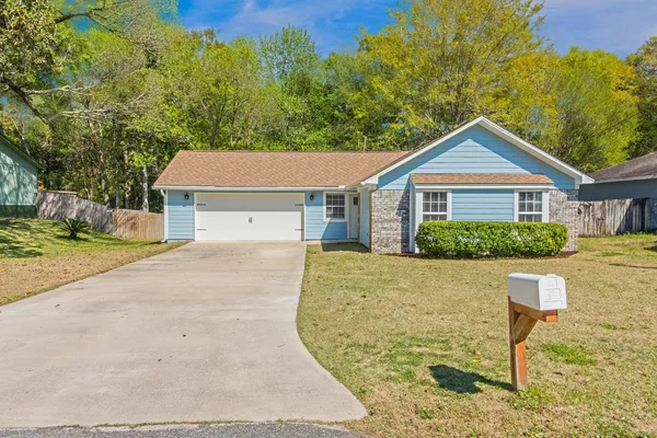 a view of a house with a yard and large tree