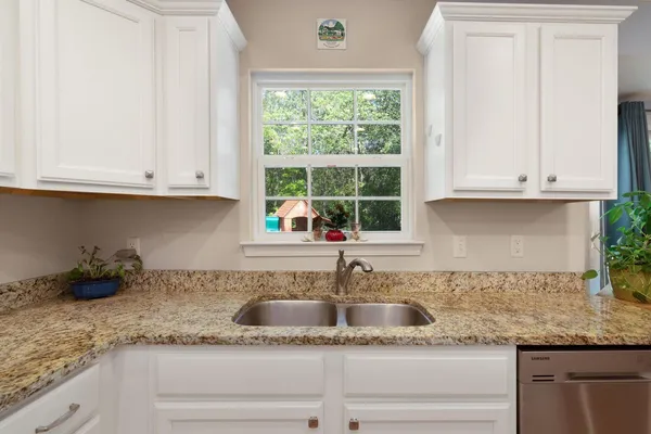 a kitchen with granite countertop white cabinets and a window