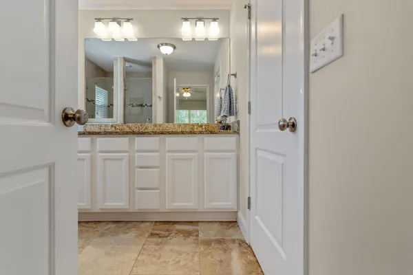 a bathroom with a granite countertop sink a mirror and a shower