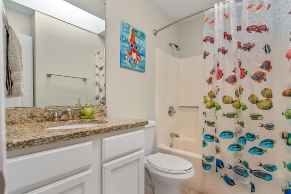 a bathroom with a granite countertop sink a toilet and a shower curtain