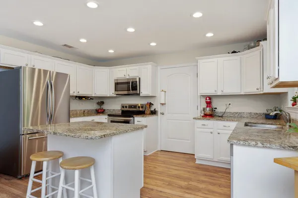 a kitchen with granite countertop a sink stainless steel appliances and white cabinets