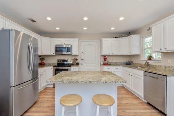 a kitchen with stainless steel appliances granite countertop a refrigerator a stove top oven a sink and cabinets