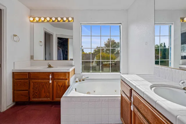a bathroom with a granite countertop tub sink and mirror