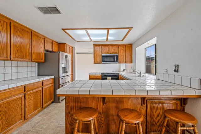 a kitchen with stainless steel appliances granite countertop a table chairs and a refrigerator