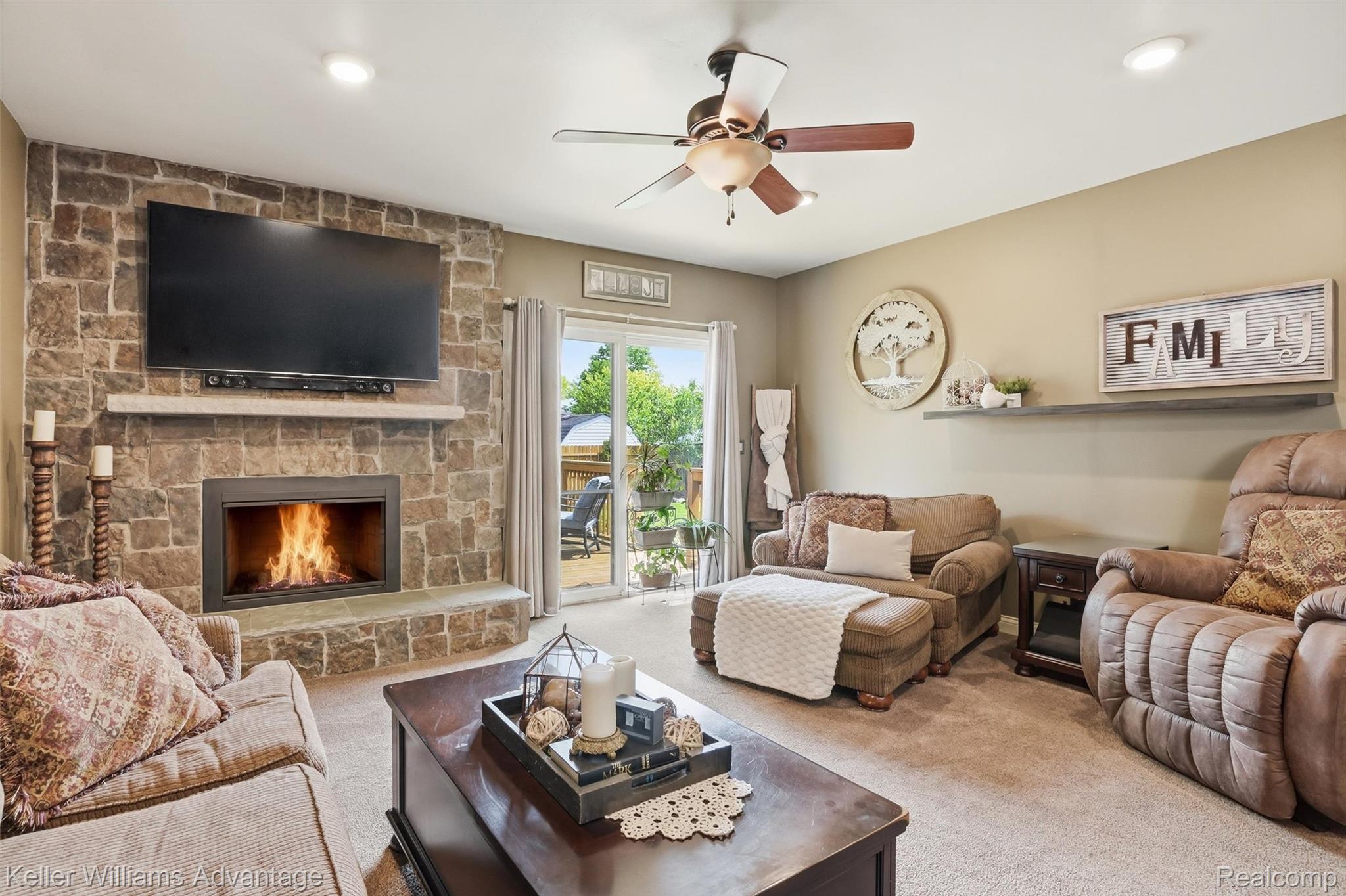 42505 Saltz Road Canton, MI 48187 - Photo 13 of 52 Living area featuring light colored carpet, a ceiling fan, and a stone fireplace