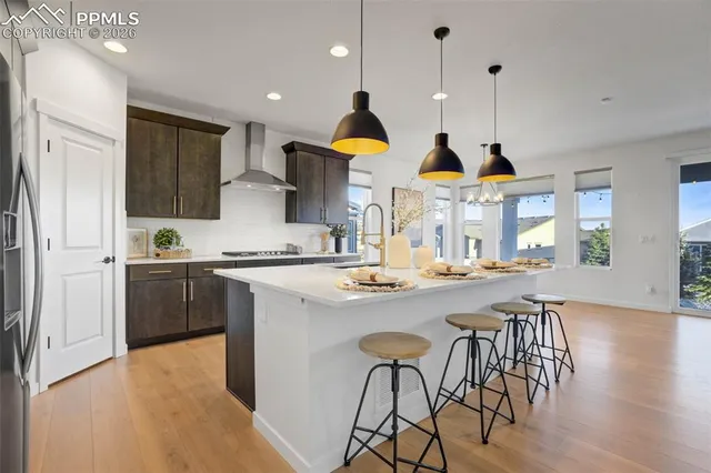 a kitchen with stainless steel appliances granite countertop a stove a sink a refrigerator and a dining table with wooden floor