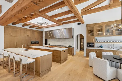 a kitchen with stainless steel appliances granite countertop a stove a refrigerator a kitchen island with couches chairs and wooden floor