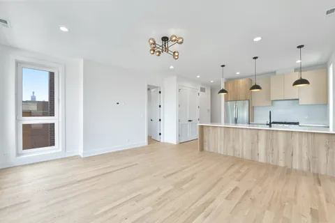 a view of a kitchen with kitchen island a sink wooden floor and a refrigerator