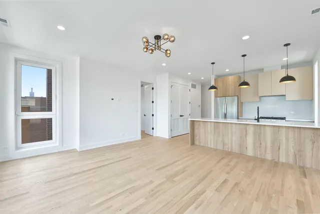 a view of a kitchen with kitchen island a sink wooden floor and a refrigerator