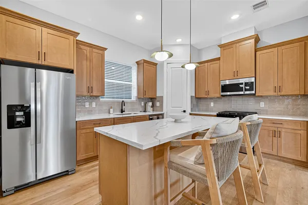 a kitchen with stainless steel appliances a stove a sink a refrigerator white cabinets and wooden floor