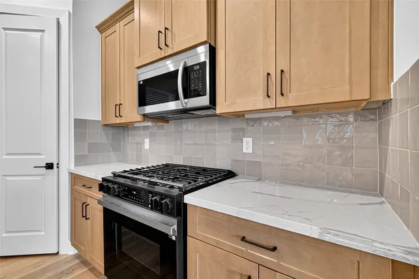 a kitchen with stainless steel appliances granite countertop white cabinets stove top oven and microwave