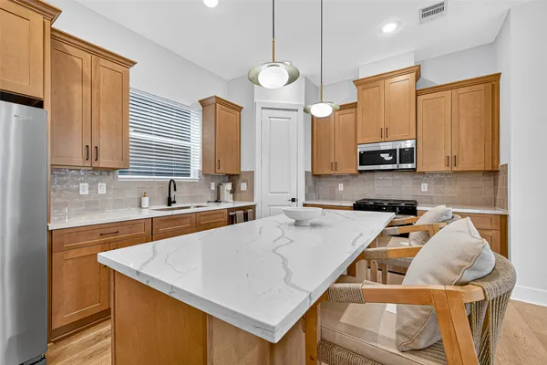 a kitchen with a stove a sink a microwave a refrigerator and cabinets