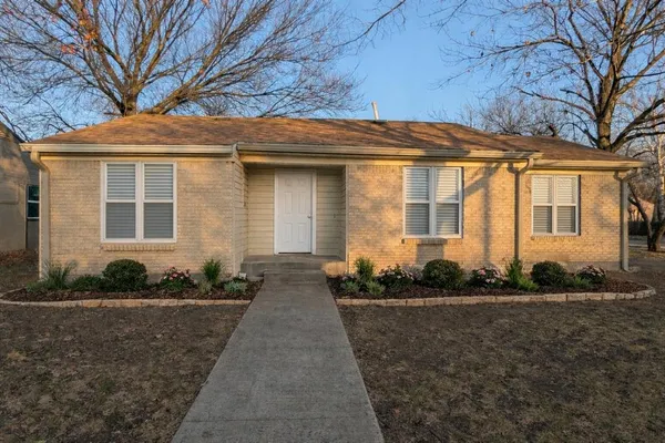 a front view of a house with plants and trees