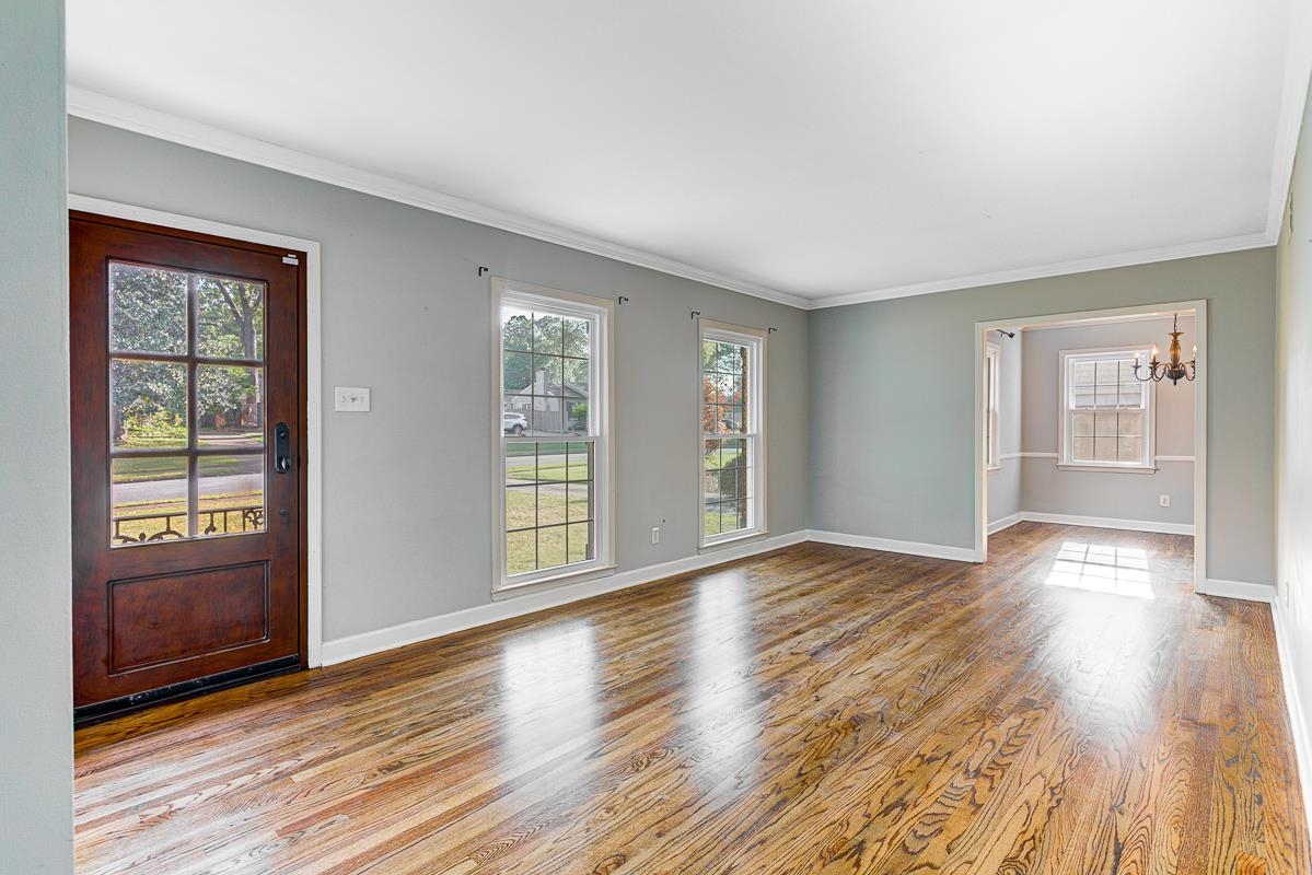 5676 Barfield Road Memphis, TN 38120 - Photo 5 of 19 Spacious room featuring wood-finish flooring, "frontporch " from Sherwin-Williams wall paint, and white crown molding