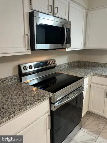a kitchen with granite countertop white cabinets and stainless steel appliances