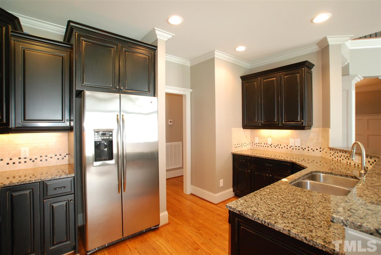 8012 Lloyd Allyns Way Raleigh, NC 27615 - Photo 10 of 25 Kitchen features Cabinets with Crown Molding, Recessed Lighting, Ceramic Backsplash & Granite Counters.