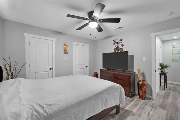 an empty room with wooden floor and ceiling fan