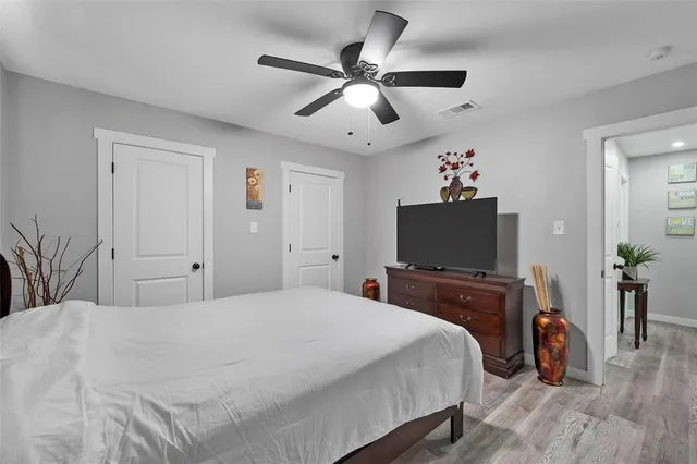 an empty room with wooden floor and ceiling fan