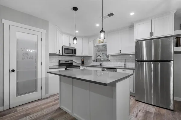 a kitchen with refrigerator a sink and a stove with wooden floor
